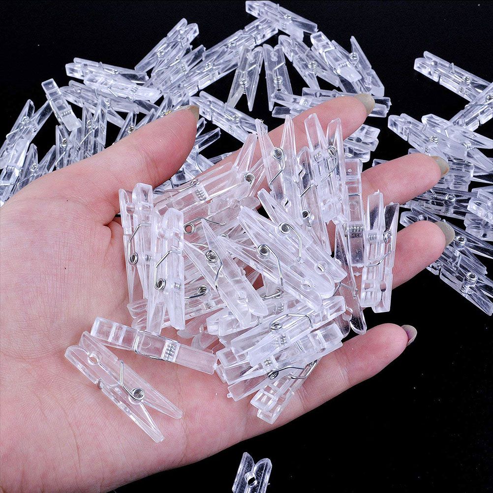 Mini Transparent Plastic clips shown as small clear plastic spring clips with visible metal pivots, piled in a hand