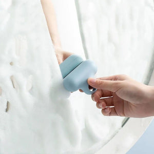 Mirror Squeegee TPR in pale blue with a rounded plastic handle and flexible blade clearing foam from a mirror
