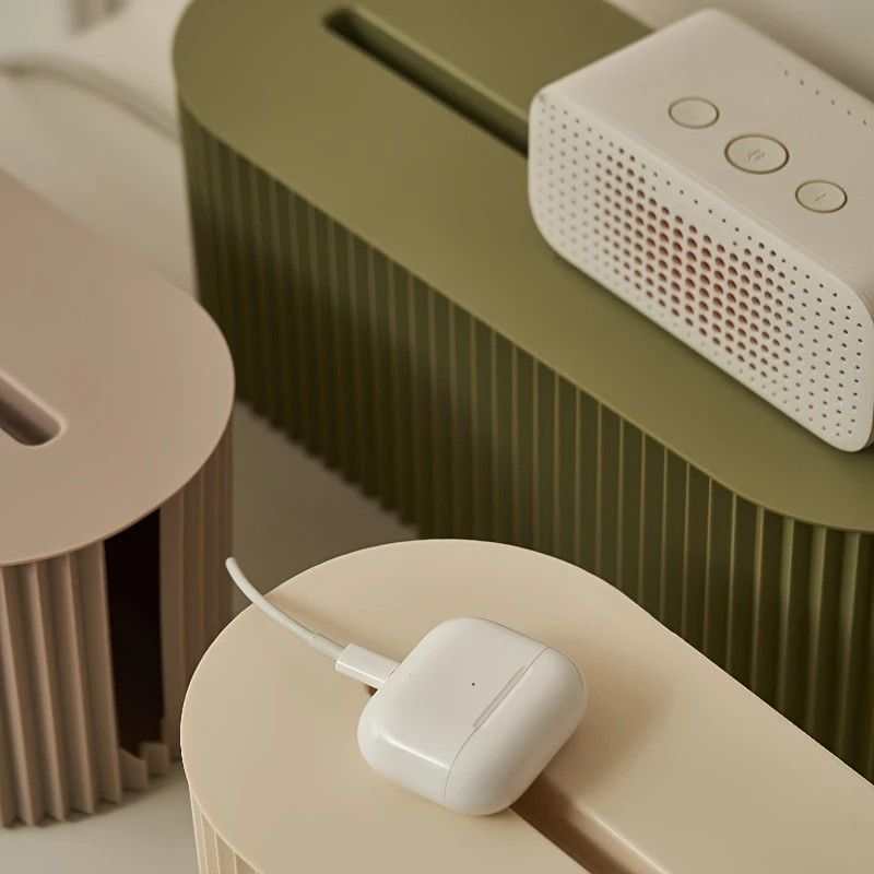 Multi-Scene Cable Storage Box with a ribbed olive-green body and rounded shape, shown holding small electronics and cables