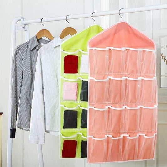 Pink wardrobe hanging storage bag with translucent multi-pocket fabric panels and white trim, shown beside a lime green organiser