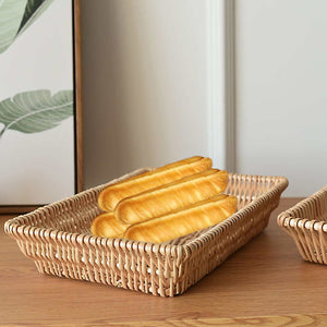 Rattan Storage Basket in natural woven rattan, rectangular with raised sides, holding several golden-brown bread rolls