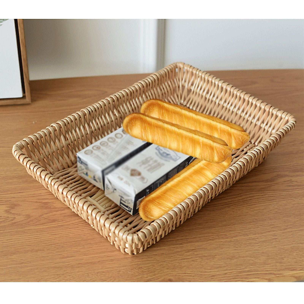 Rattan Storage Basket in natural woven material, rectangular with raised edges, holding bread rolls and packaged snacks