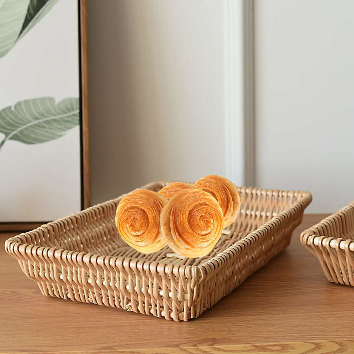 Rattan Storage Basket in natural woven rattan, a shallow rectangular tray holding two golden spiral pastries