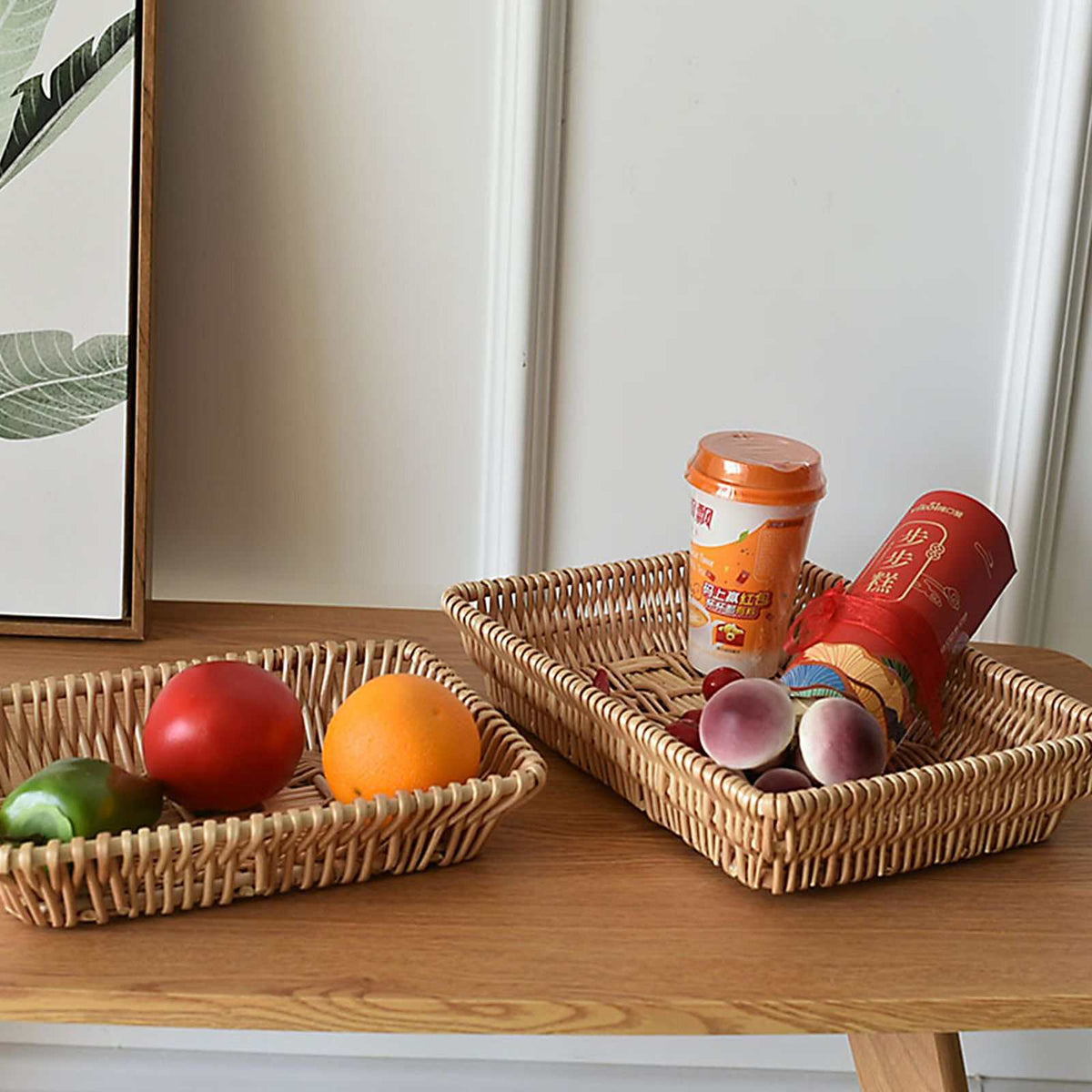 Rattan Storage Basket set in natural woven rattan, featuring two shallow rectangular trays holding fruit and packaged snacks