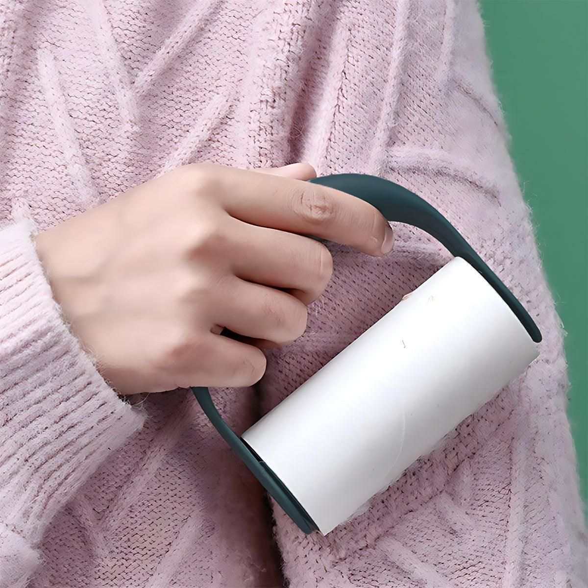 Reusable Lint Roller with dark green handle and white adhesive roll held by hand over pink knitted fabric for lint removal