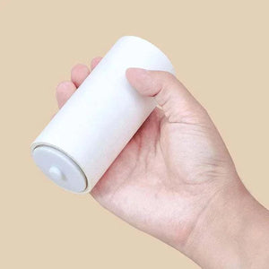 Reusable Lint Roller held in hand featuring white paper roll and white plastic core for removing lint and pet hair