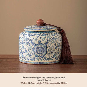 Ru Kiln tea jar in glossy white ceramic with intricate blue floral scrollwork, a fitted lid and decorative tassel