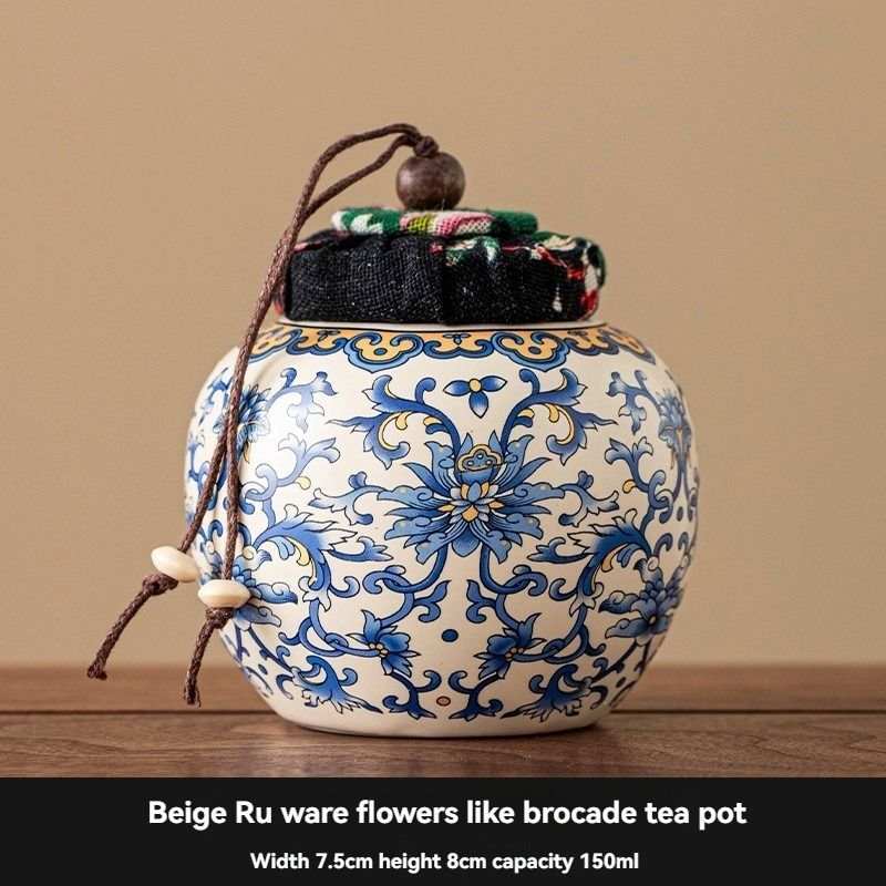 Ru Kiln tea jar in cream ceramic with ornate blue floral scrollwork, rounded body, and a fabric-topped corded lid