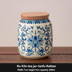 Ru Kiln tea jar in cream ceramic with ornate blue floral scrollwork and a flat, natural wood-toned lid