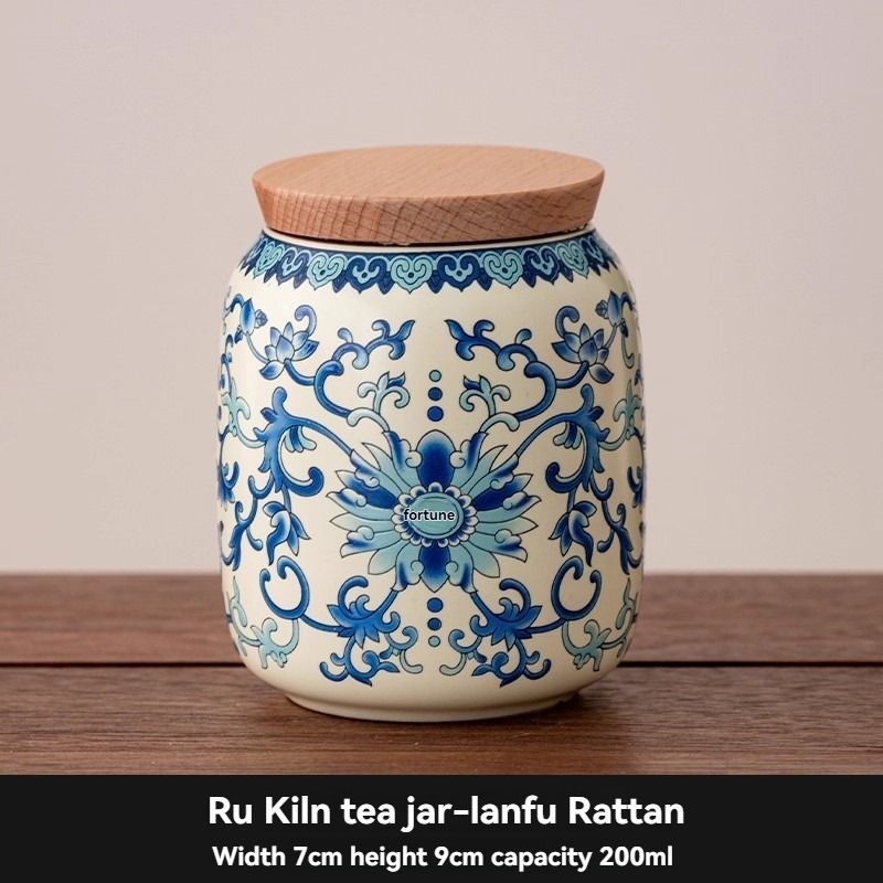 Ru Kiln tea jar in cream ceramic with ornate blue floral scrollwork and a flat, natural wood-toned lid