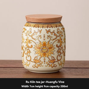 Ru Kiln tea jar in cream ceramic with an ornate gold floral vine pattern and a flat wooden lid