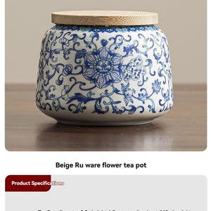 Ru Kiln tea jar in white ceramic with cobalt blue floral scrollwork, rounded body and pale beige lid.