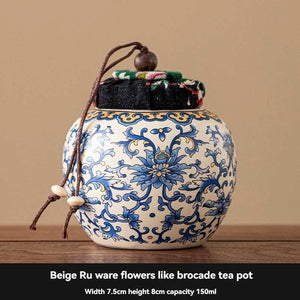 Ru Kiln tea jar in white ceramic with ornate blue floral pattern, rounded shape and fabric-covered lid with hanging cord