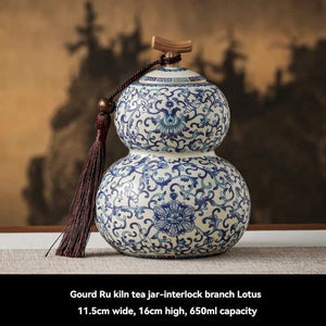 Ru Kiln tea jar in white ceramic with intricate blue floral scrollwork, a double-gourd shape, and a tasselled lid
