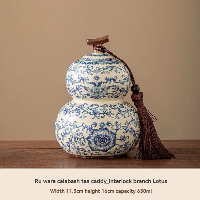 Ru Kiln tea jar in white ceramic with intricate blue floral patterns, a double-gourd shape and decorative tassel