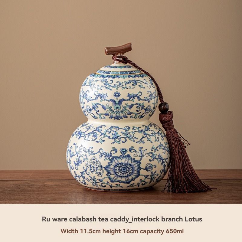 Ru Kiln tea jar in white ceramic with intricate blue floral and vine patterns, rounded double-gourd shape and tassel