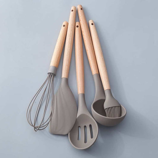 Silicone Kitchen Utensil set with gray silicone heads and pale wood handles, including a whisk, spoon, turner and ladle