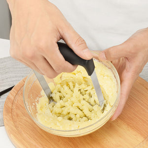 Stainless Steel Potato Masher with black wide-grip handle and twin metal mashing arms pressing cooked potatoes