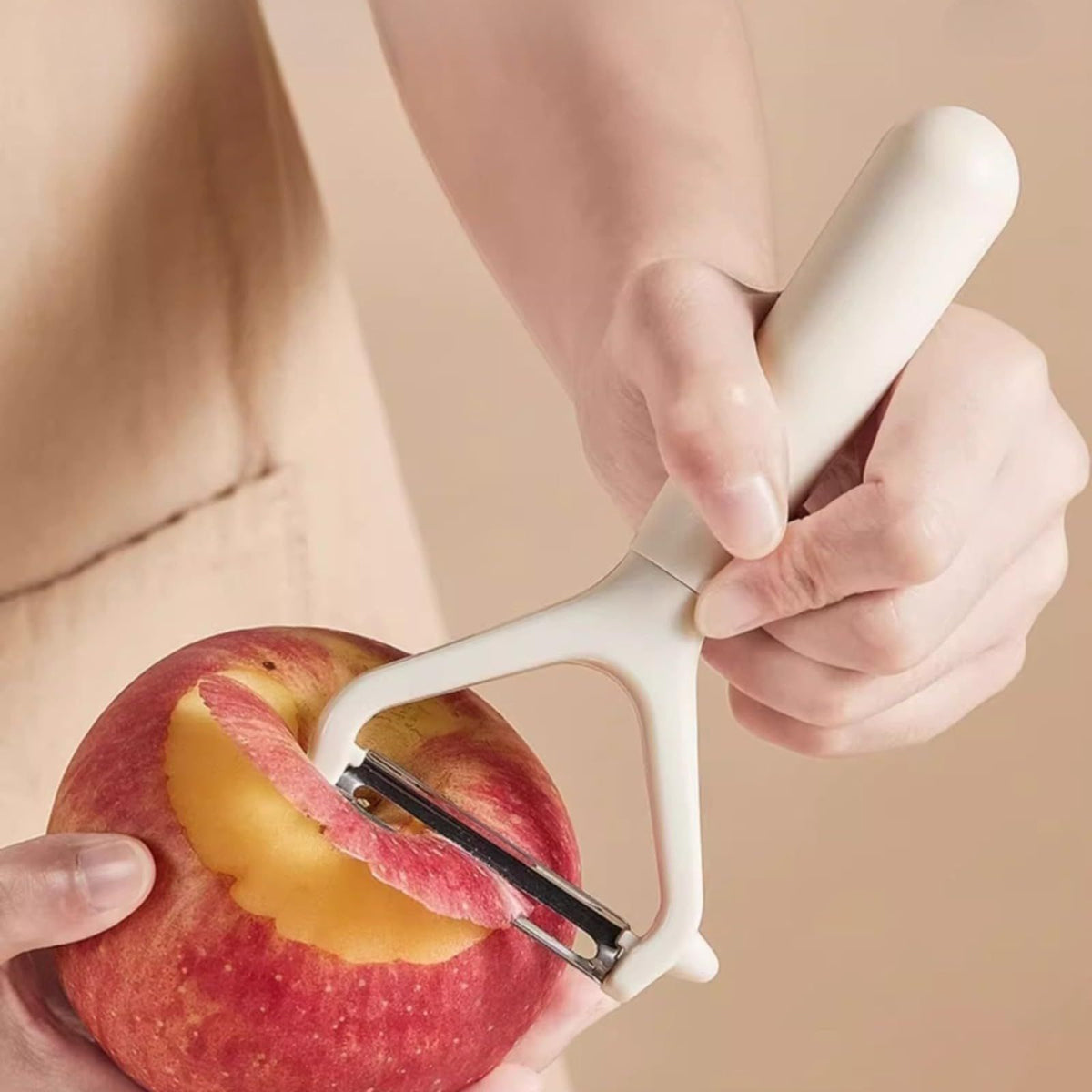 Swivel Vegetable Peeler with a white ergonomic handle and stainless steel blade peeling a red apple