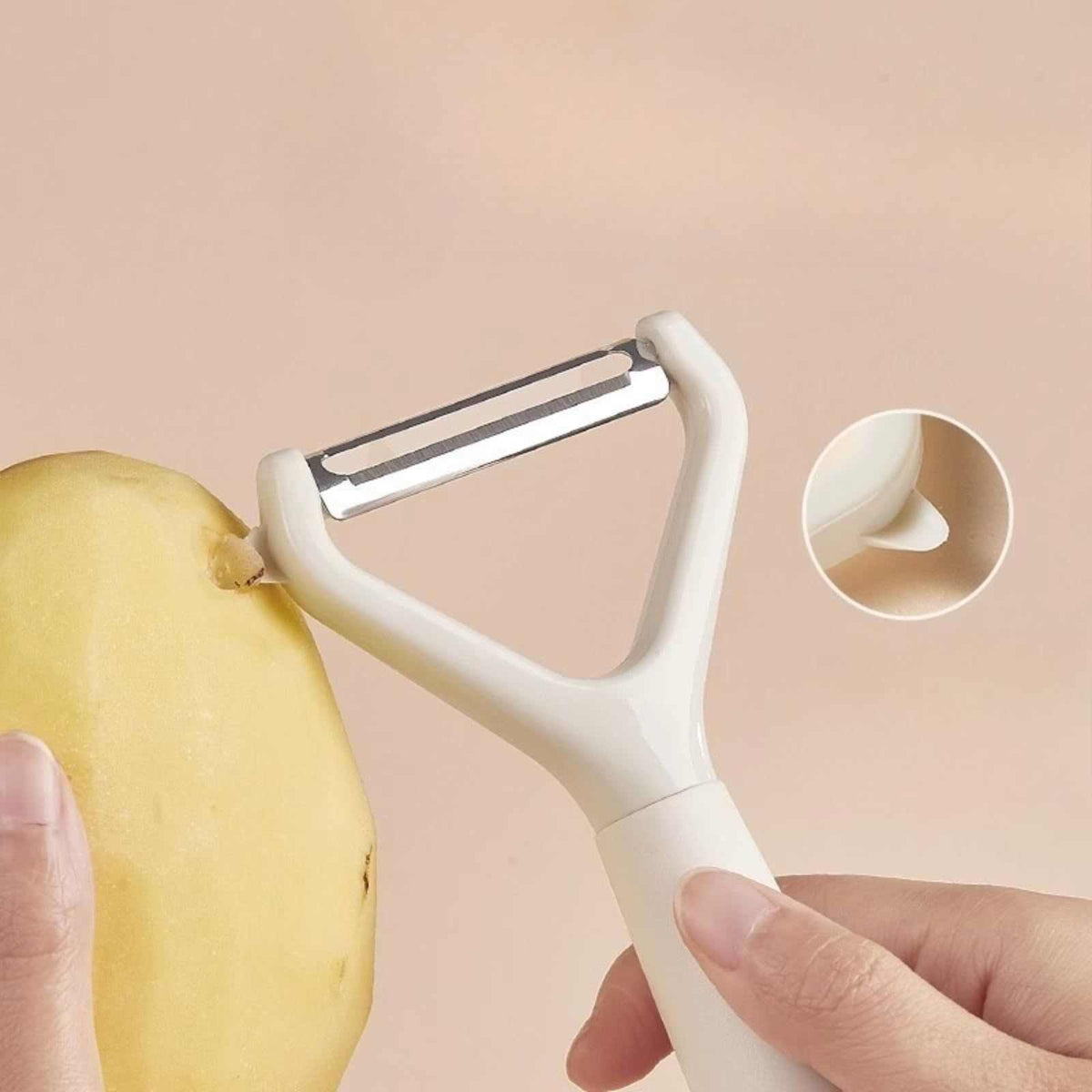 Swivel Vegetable Peeler with a white plastic Y-shaped handle and stainless steel blade peeling a potato