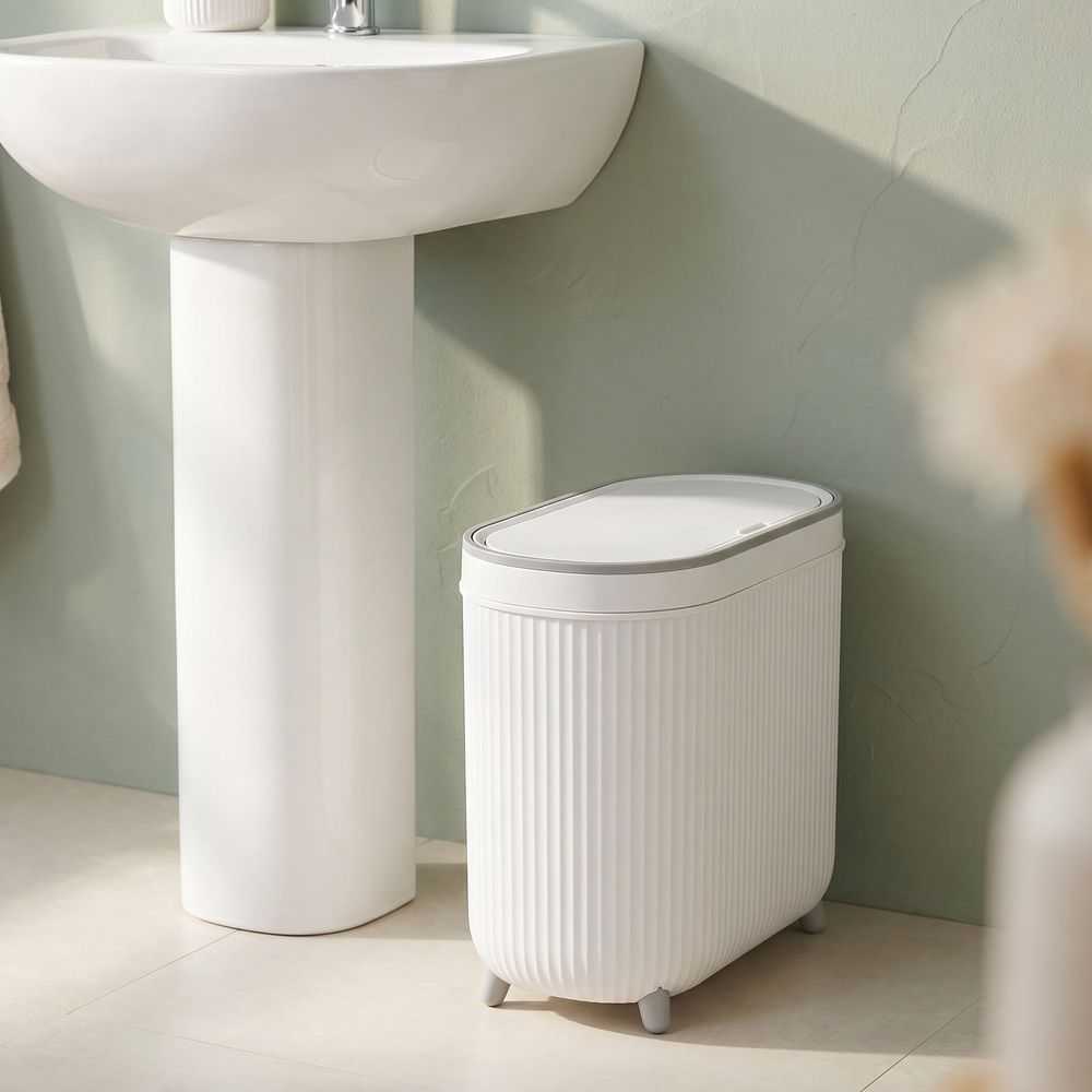 White Plastic Trash Can with a slim rectangular body, vertical ribbed texture, fitted lid and four short feet